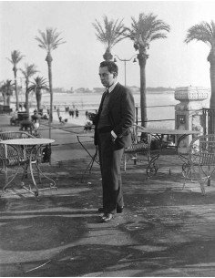 Man Ray (Cannes)   Man Ray standing in a suit, on a café terrace on...