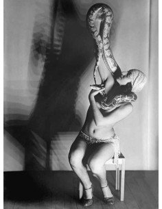 Mlle Dorita charmeuse de serpents, torse nu, assise soulevant le se...